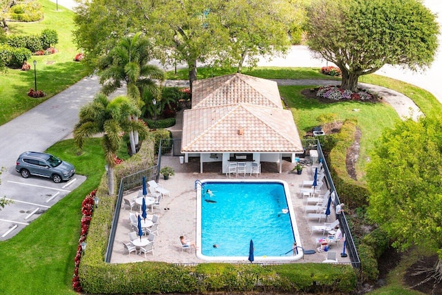 community pool featuring a patio area, a yard, and fence