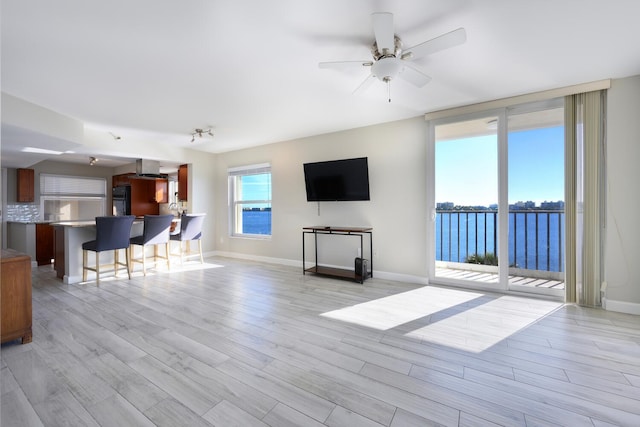 living area with light wood-style floors, floor to ceiling windows, baseboards, and a ceiling fan