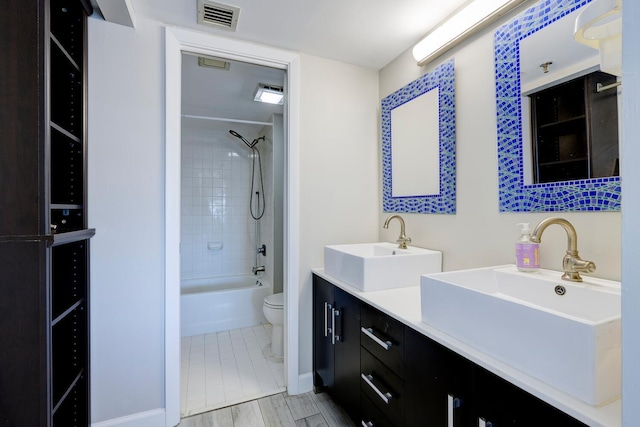 full bathroom featuring toilet, double vanity, visible vents, and a sink