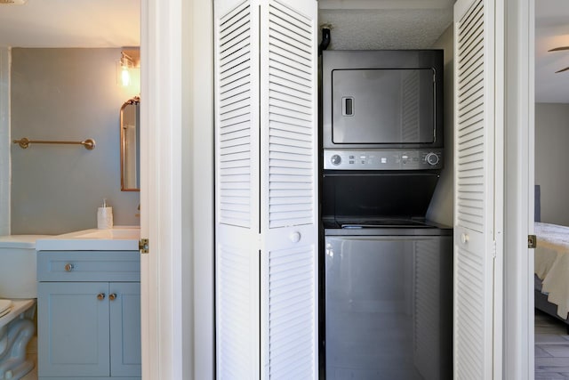 laundry area with a textured ceiling, laundry area, and stacked washer / drying machine