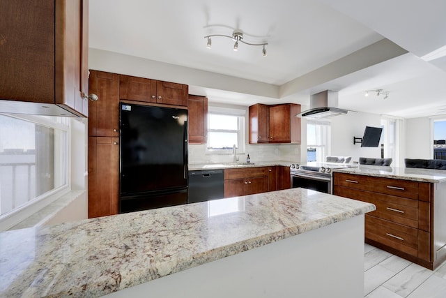 kitchen featuring a peninsula, wall chimney exhaust hood, backsplash, light stone countertops, and black appliances