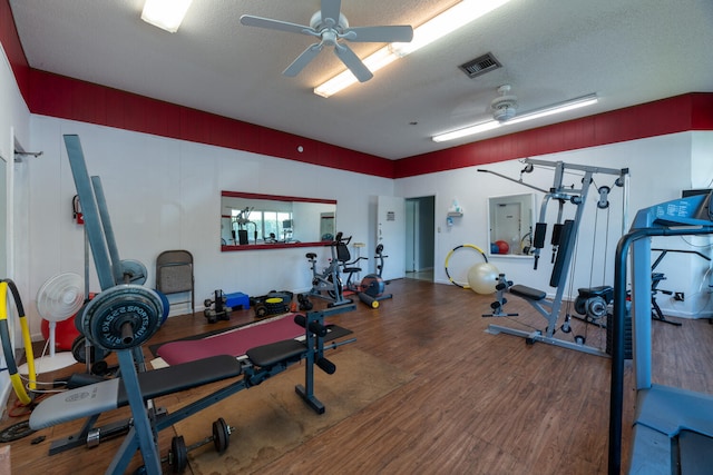 workout area featuring a textured ceiling, wood finished floors, visible vents, and a ceiling fan