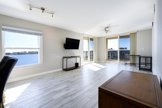 unfurnished living room with light wood-style floors, a healthy amount of sunlight, and baseboards