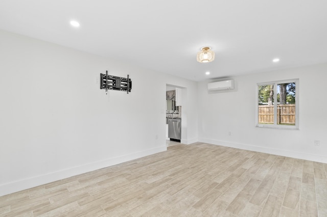 unfurnished room with light wood-style floors, recessed lighting, an AC wall unit, and baseboards