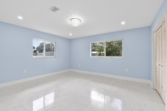 unfurnished bedroom with baseboards, visible vents, and speckled floor