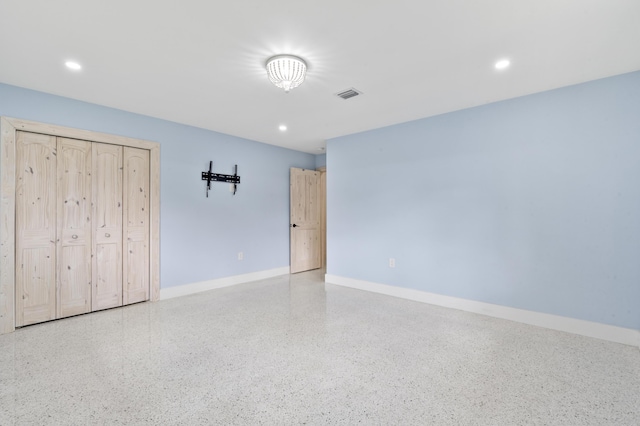 unfurnished bedroom with baseboards, visible vents, speckled floor, and recessed lighting