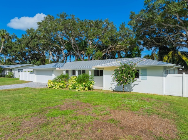 single story home with metal roof, fence, driveway, stucco siding, and a front yard