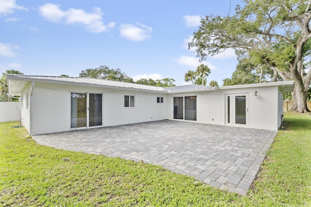 back of house with metal roof, a yard, and stucco siding