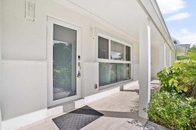 property entrance with covered porch and stucco siding