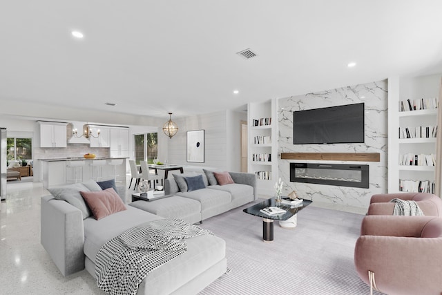 living area with built in features, a fireplace, recessed lighting, visible vents, and a chandelier