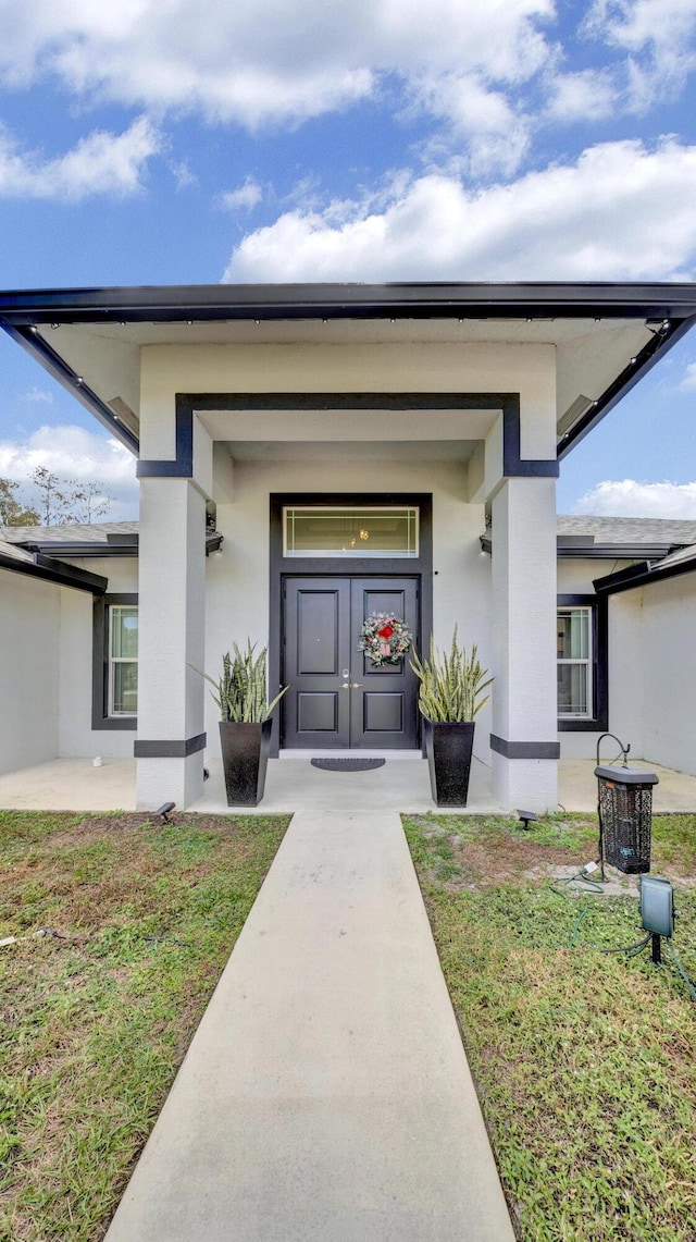 entrance to property with a lawn and stucco siding