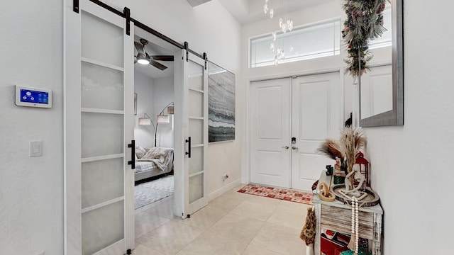 interior space with a barn door, french doors, and light tile patterned flooring