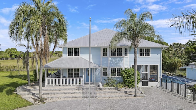 view of front of property with metal roof, a porch, a sunroom, a standing seam roof, and a front yard