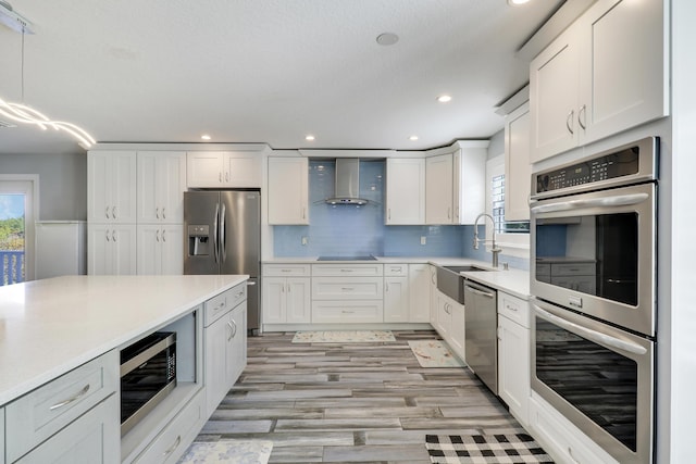 kitchen featuring wall chimney range hood, a wealth of natural light, stainless steel appliances, and a sink