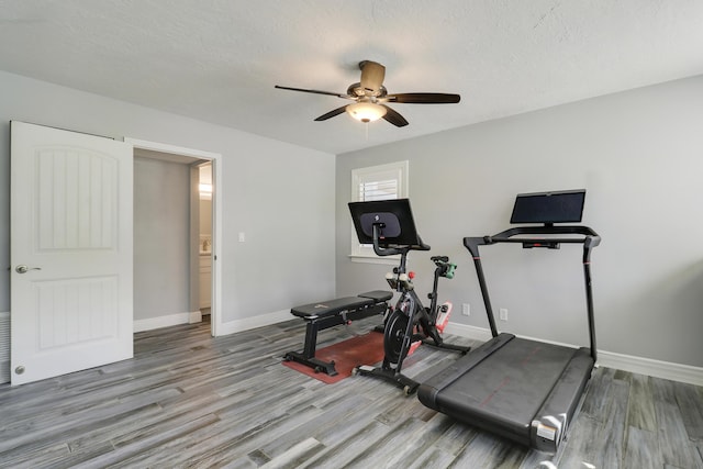 workout room with ceiling fan, a textured ceiling, baseboards, and wood finished floors