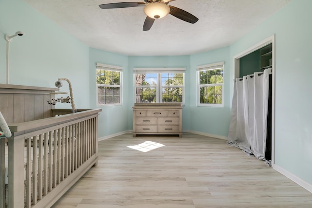 unfurnished bedroom featuring a textured ceiling, multiple windows, wood finished floors, and baseboards