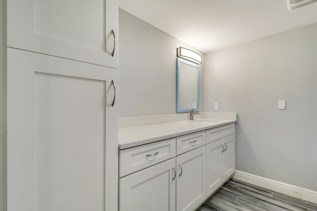 bathroom featuring visible vents, wood finished floors, vanity, and baseboards