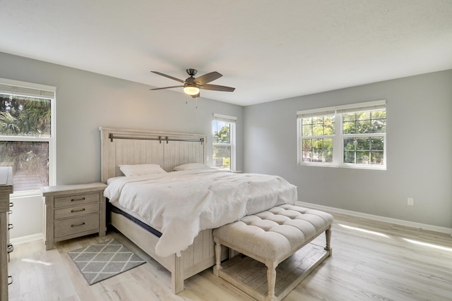 bedroom featuring light wood-style flooring, baseboards, and ceiling fan