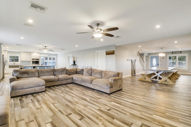 living room featuring light wood finished floors, recessed lighting, visible vents, stairway, and baseboards