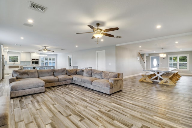 living area with recessed lighting, visible vents, baseboards, light wood-style floors, and stairway