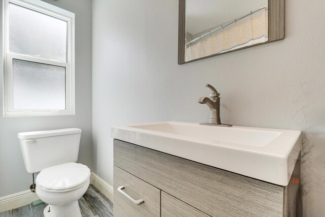 bathroom with baseboards, vanity, and toilet