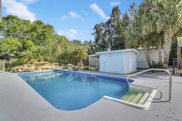 view of pool with fence, an outdoor structure, a fenced in pool, and a patio