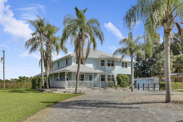 view of front of home featuring metal roof, fence, decorative driveway, a porch, and a front yard