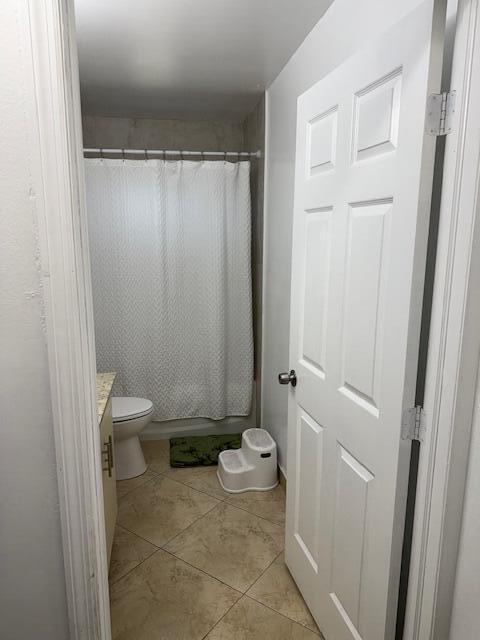 full bath with toilet, tile patterned flooring, shower / bath combination with curtain, and vanity