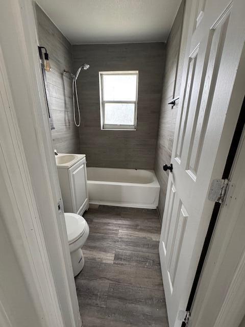 full bathroom with tub / shower combination, vanity, toilet, and wood finished floors