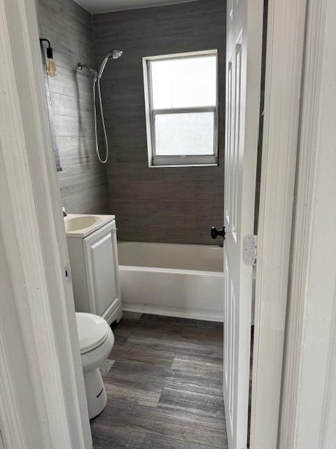 full bath featuring wood finished floors, shower / bath combination, vanity, and toilet