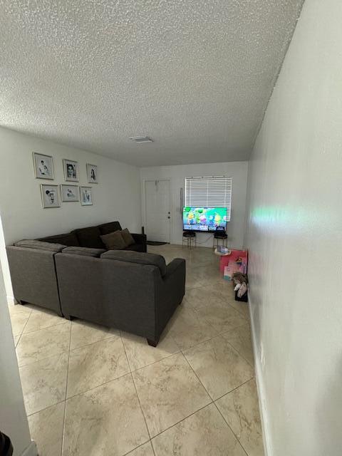 living area with a textured ceiling, light tile patterned floors, and visible vents