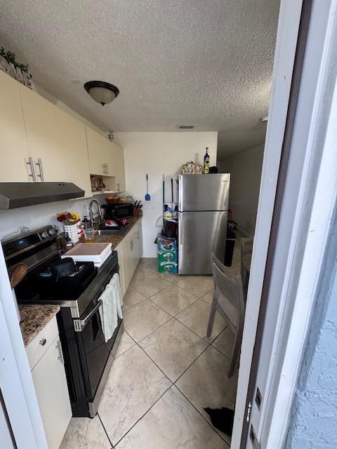 kitchen featuring a sink, white cabinetry, exhaust hood, freestanding refrigerator, and black electric range oven