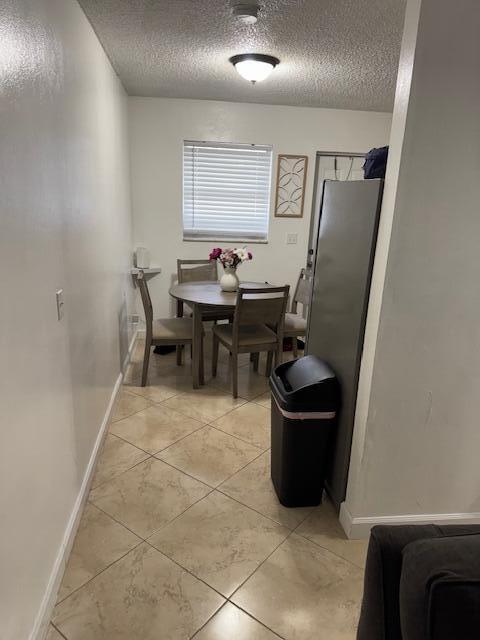 dining room featuring a textured ceiling, light tile patterned floors, and baseboards