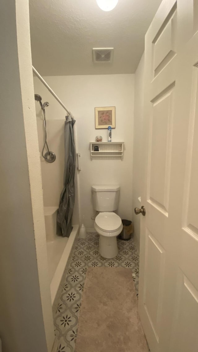 bathroom with a shower with shower curtain, visible vents, and toilet