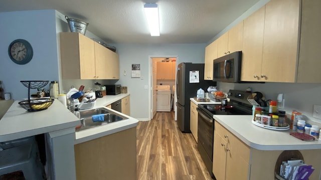 kitchen with a peninsula, appliances with stainless steel finishes, light countertops, and light wood-style floors