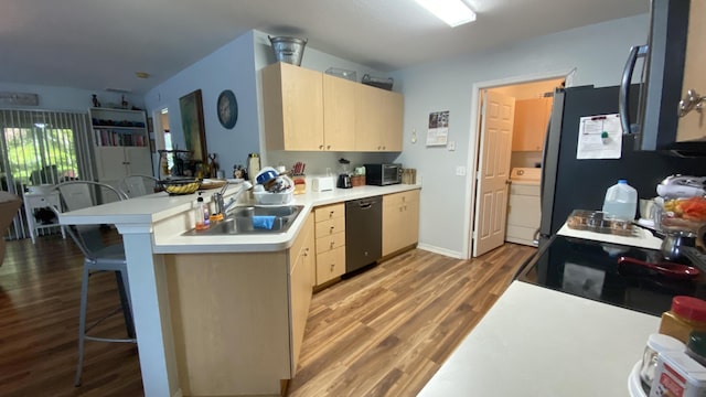 kitchen featuring washer / clothes dryer, a breakfast bar area, a peninsula, light countertops, and black appliances