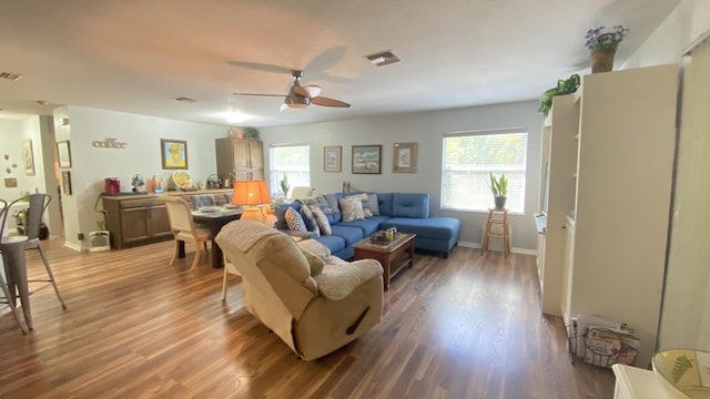 living room with baseboards, wood finished floors, visible vents, and a ceiling fan