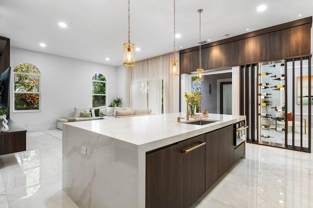 kitchen featuring stainless steel oven, a sink, dark brown cabinetry, and modern cabinets