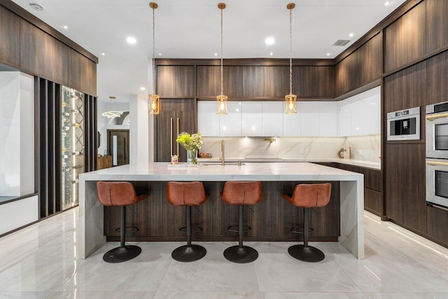 kitchen featuring visible vents, a spacious island, modern cabinets, backsplash, and a sink