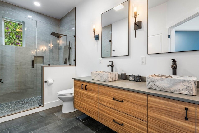 bathroom with toilet, a shower stall, double vanity, and a sink