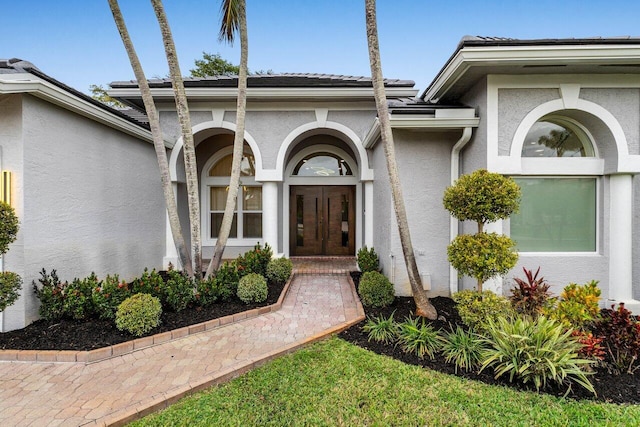 entrance to property featuring french doors and stucco siding