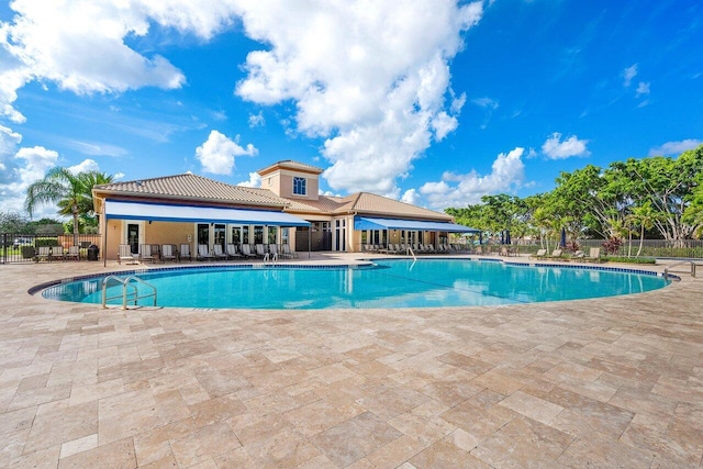 community pool with a patio and fence