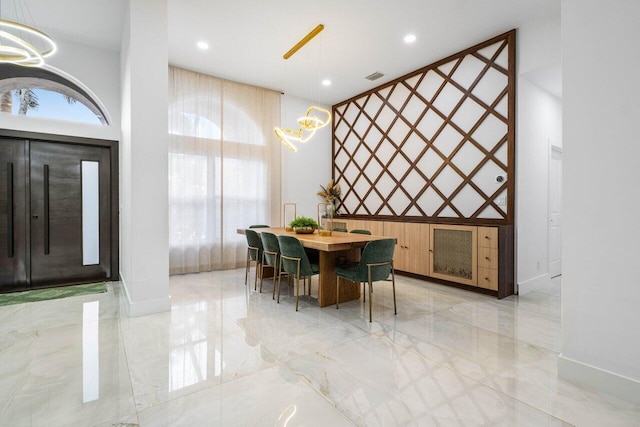 dining room featuring marble finish floor, visible vents, a towering ceiling, and baseboards