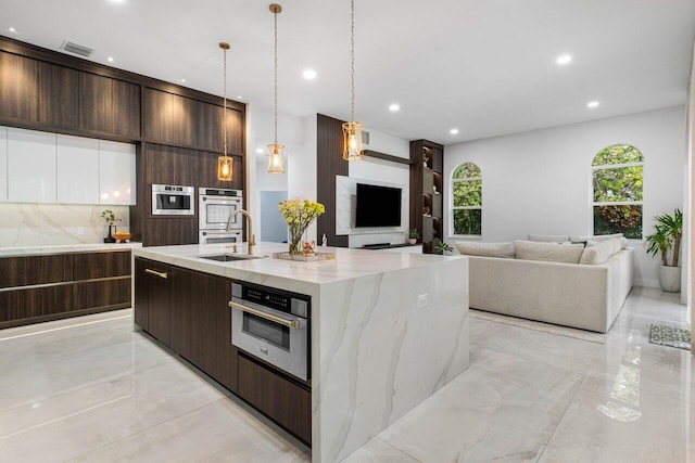 kitchen featuring open floor plan, modern cabinets, a sink, and dark brown cabinetry