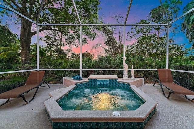 view of swimming pool featuring glass enclosure, a patio area, and a jacuzzi