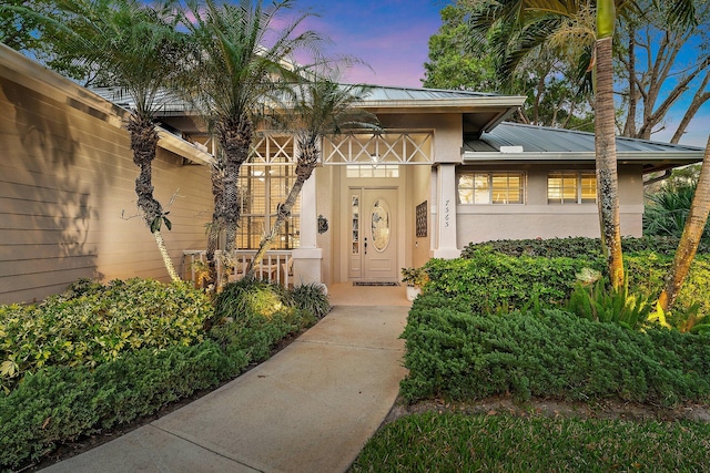 7565 SE Teton Dr, Hobe Sound, FL 33455 - view of exterior entry with stucco siding, a standing seam roof, and metal roof