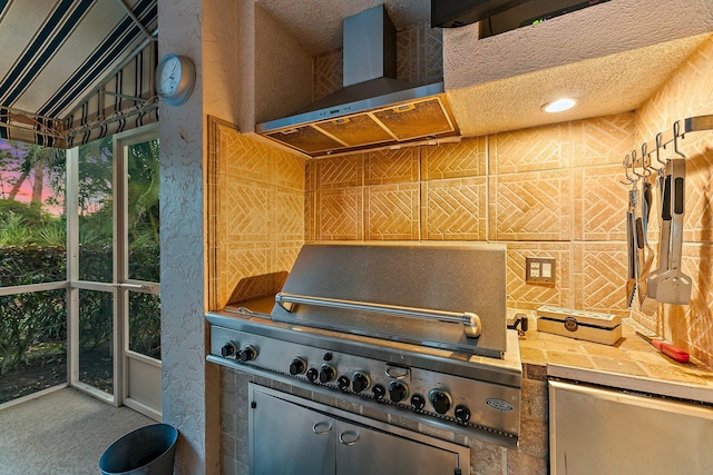 kitchen featuring tile countertops, wall chimney exhaust hood, and a textured ceiling