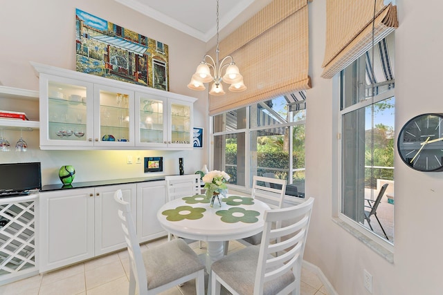 dining area with light tile patterned floors, ornamental molding, baseboards, and an inviting chandelier