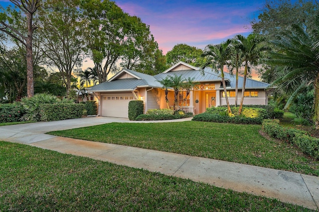 7565 SE Teton Dr, Hobe Sound, FL 33455 - ranch-style house featuring a front lawn, metal roof, covered porch, concrete driveway, and an attached garage