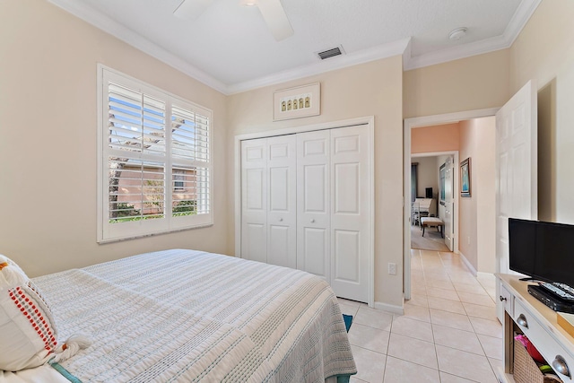 bedroom with a closet, light tile patterned flooring, visible vents, and crown molding